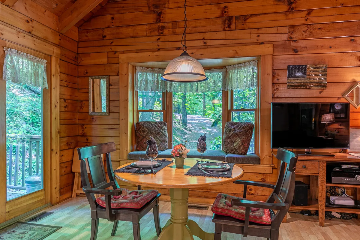 An intimate round dining table set beside bay windows, surrounded by tasteful decorative accents. The windows offer sunrise views and a flood of natural light, creating an ideal spot for cozy meals or a morning coffee.