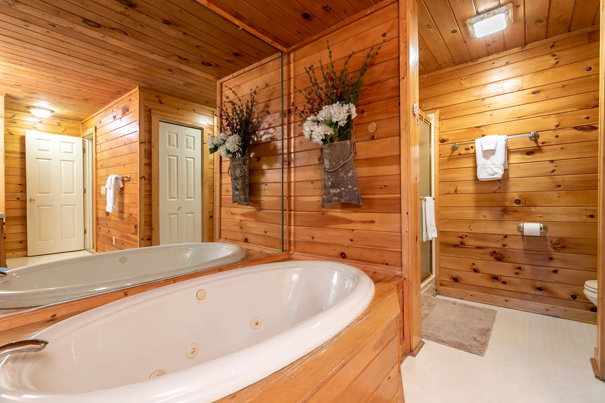 A serene bathroom space featuring a deep spa tub surrounded by warm wood paneling and decorative planters. The soft lighting and tranquil design promise relaxation and rejuvenation after a day of mountain adventure.